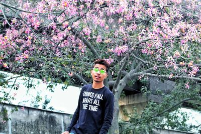 Portrait of young man standing by flowering plants