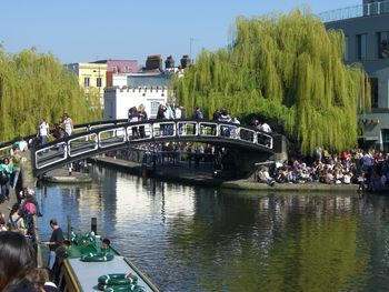 People on bridge over river in city against clear sky