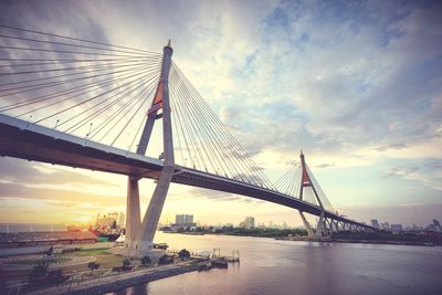 Suspension bridge over river against sky during sunset