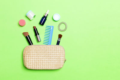 Directly above shot of purse with beauty products over green background