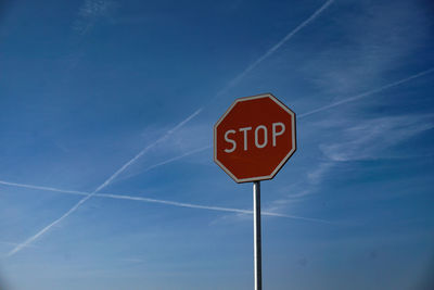 Low angle view of road sign against blue sky