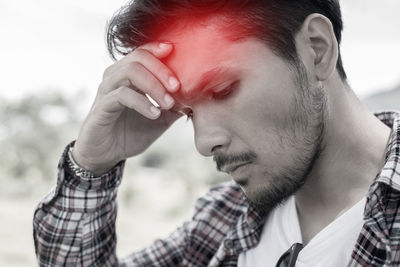 Man with headache against sky