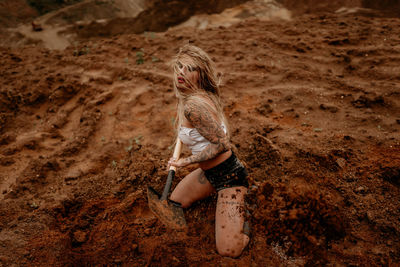 Young girl digs sand with a shovel