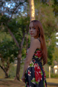 Portrait of woman standing against tree