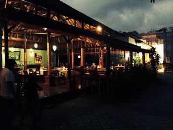 People on illuminated restaurant by building at night