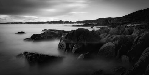 Scenic view of rocks in sea against sky