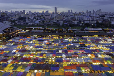 High angle view of illuminated colorful tents against cloudy sky at night