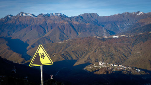 Road sign by mountains against sky