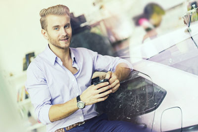 Double exposure of man holding coffee cup at cafe and car