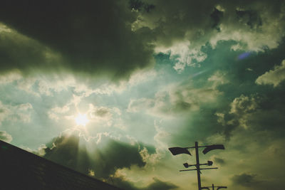 Low angle view of sun shining through clouds