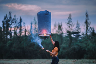 Side view of woman holding illuminated paper lantern