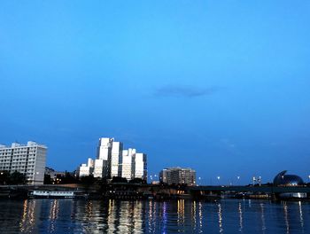 River by buildings against blue sky