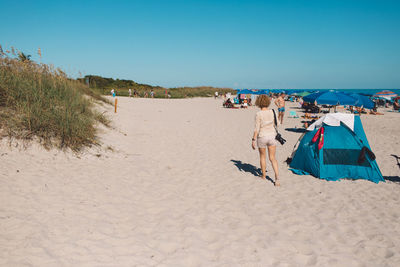 People on beach against clear sky