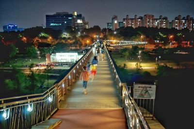Illuminated bridge over river in city at night