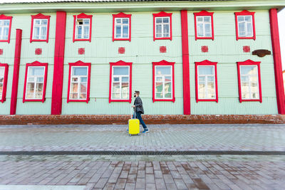 Rear view of woman walking on footpath against building