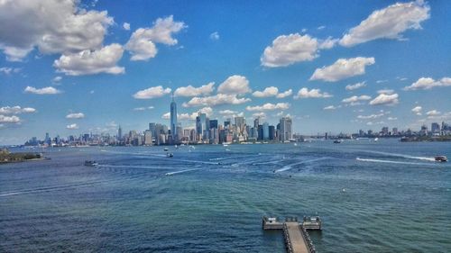 View of city by sea against cloudy sky