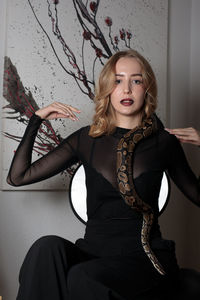 Portrait of young woman standing against wall