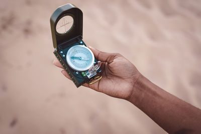 From above of crop unrecognizable female explorer navigating with magnetic compass while standing on sandy terrain during summer adventure