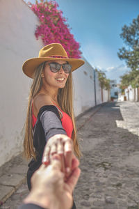 Portrait of woman wearing hat standing on footpath