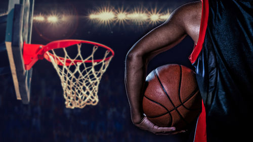 Midsection of man holding basketball