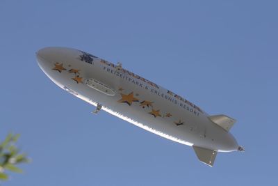 Low angle view of airplane flying against clear blue sky