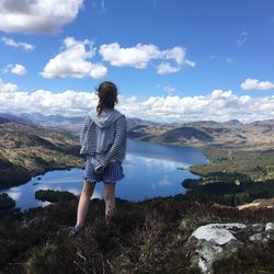 Rear view of woman standing by mountain against sky