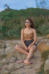 Portrait of young woman sitting on land