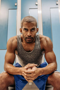 Determined male athlete with muscular build sitting in locker room