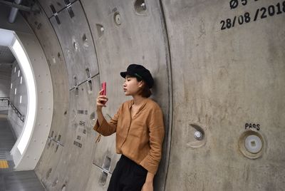 Woman using phone while standing in tunnel