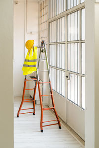 Hardhat and reflective waistcoat hanging on ladder in empty studio