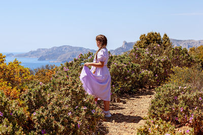 Woman standing by plants against sky