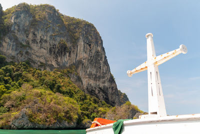 Low angle view of cross on rock against sky