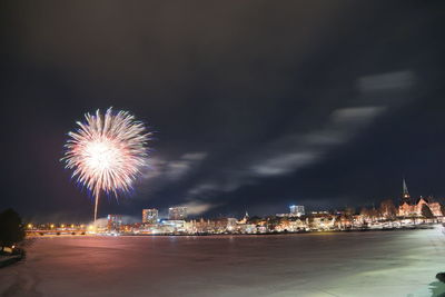 Firework display over illuminated buildings in city at night