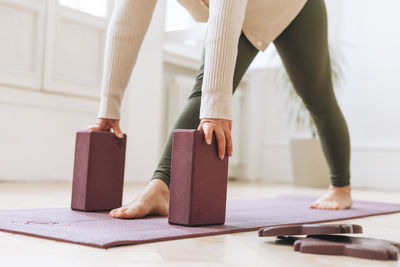 Attractive middle aged woman in sportswear ptactice yoga with equipment in light studio