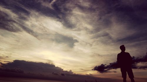 Rear view of silhouette man standing against sky during sunset