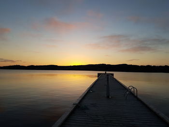 Pier over lake against sky during sunset