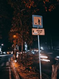 Road sign by street in city at night