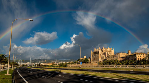 Rainbow over road in city against sky