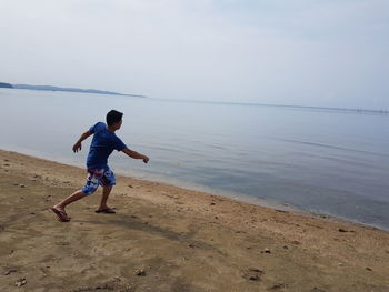 Man playing at beach against sky