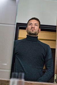 Portrait of young man sitting against ceiling