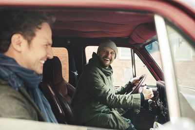 Happy male friends in camping van during road trip