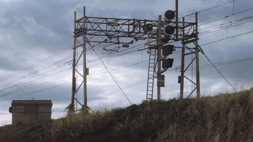 Low angle view of electricity pylon on field against sky