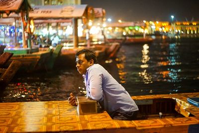 Man using mobile phone while sitting in city at night