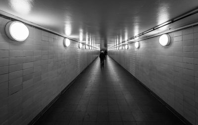 Rear view of man walking in subway tunnel