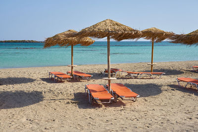 Deck chairs on beach against clear sky