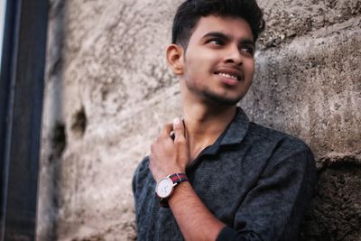 Portrait of smiling young man against wall