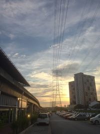 Cars on road amidst buildings against sky during sunset