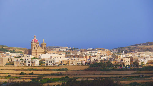 Panoramic view of buildings in city against clear blue sky