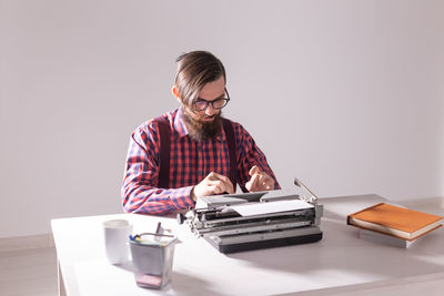 Mid adult man using smart phone while sitting on table