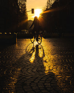 Man riding bicycle on street in city at sunset